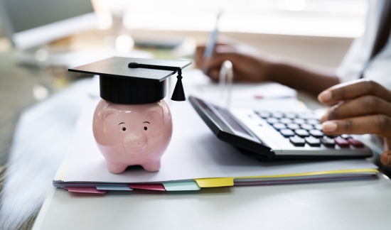 Student using calculator next to piggy bank