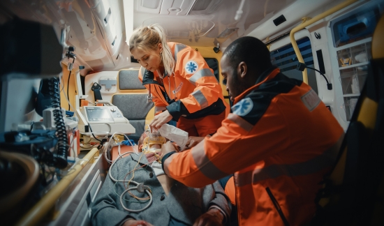 Female and male paramedic inside ambulance attending a person.