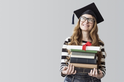 Photo of female college graduate carrying books and a diploma