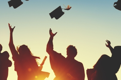 Photo of college graduates throwing their caps to the sky