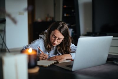 Female student writing by laptop