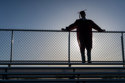 high school graduate standing at the top of the bleachers.